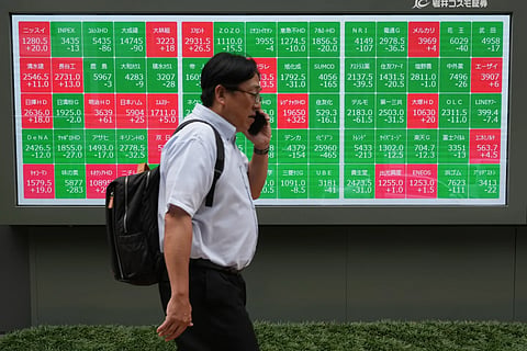 A man walks past a monitor showing stock prices of companies on the Tokyo Stock Exchange, Tokyo , Tuesday, June 23, 2026.