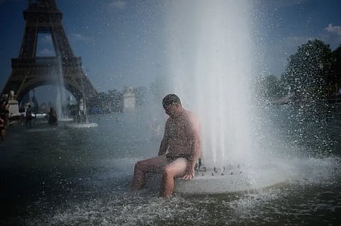 A person cools off at Trocadero fountain near the Eiffel Tower during a heat wave in Paris, Wednesday, June 24, 2026.