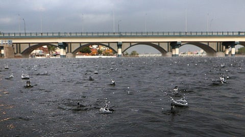 Raindrops ripple across the waters of the Vaigai River beneath a brooding evening sky in Madurai.