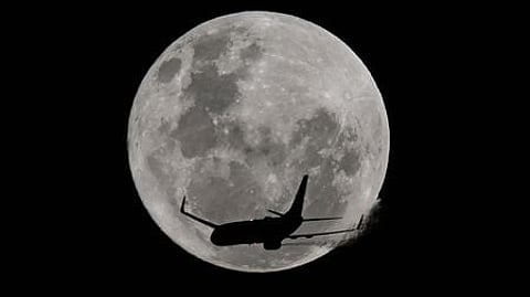 An aircraft passes in front of the full moon, known as the 'Strawberry Moon' over Coogee Beach in Sydney on June 11, 2025.