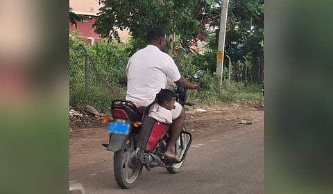 The child seated inside the side bag of a motorcycle in Gadag.