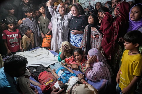 Women mourn next to the bodies of their children killed after the roof of a tutoring center under-construction collapsed, on the outskirts of Lahore, Pakistan, Tuesday, June 30, 2026.