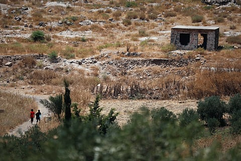 Two boys walk along a road near a damaged building in the village of Abdin, Daraa province, Syria, Monday, June 29, 2026, after local residents said Israeli forces carried out an incursion into the area a day earlier.