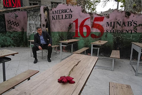 A man sits on a bench in a memorial, set for the school children who were killed during a strike on a primary school in southern town of Minab on Feb. 28, in northern Tehran, Iran, Sunday, April 12, 2026.