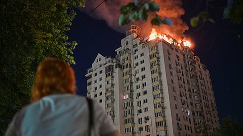 A woman looks at an apartment building burning after a Russian missile attack in Kyiv, Ukraine, Thursday, July 2, 2026.