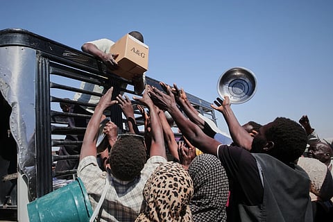 Sudanese families displaced from El-Fasher reach out as aid workers distribute food supplies at the newly established El-Afadh camp in Al Dabbah, in Sudan’s Northern State, Nov. 16, 2025.