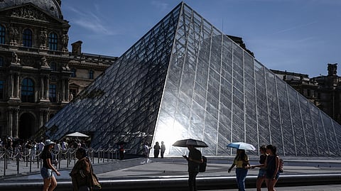 Tourists walk past the Louvre Museum in Paris on May 28, 2026, as a heatwave hits France.