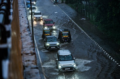 Commuters drive through waterlogged service road in heavy rain near CRP Square in Bhubaneswar on Friday.