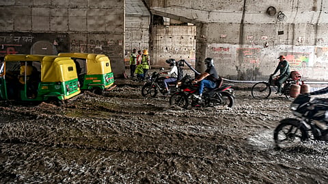 Commuters move on a waterlogged road following heavy rainfall on Saturday.