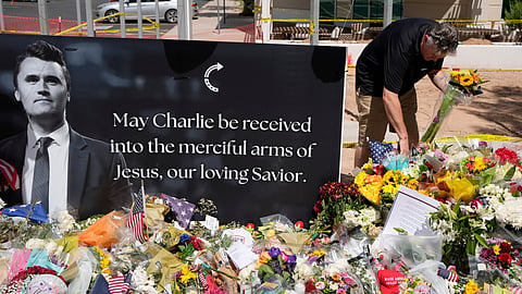 A well-wisher places flowers at a makeshift memorial set up for Charlie Kirk at Turning Point USA headquarters, Sept. 11, 2025, in Phoenix.