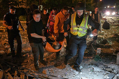 Emergency workers carry an injured person following Russian missile attacks in Kyiv, Ukraine, Monday, July 6, 2026.