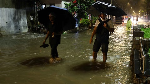 Commuters wade through waterlogged Nagardas Road amid heavy monsoon rains, at Andheri East area, in Mumbai, Maharashtra, late Sunday, July 5, 2026.