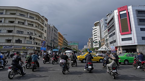 Motorbikes and cars pass through an intersection in downtown Tehran, Iran, May 17, 2026.