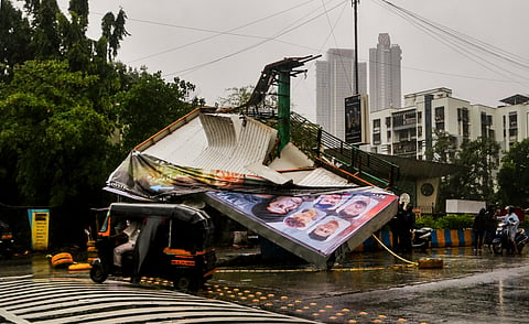 A hoarding lies damaged after strong winds uproot it from a road divider on Pokhran Road amid heavy rainfall, in Thane, Maharashtra, Monday, July 6, 2026.