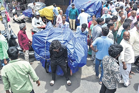 Hawkers removing their stalls as VMC workers arrive to remove them at Besant Road in Vijayawada.