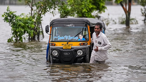 A driver pulls his auto-rickshaw on a waterlogged road after heavy rainfall, at Vasai-Virar in Maharashtra’s Palghar district on Wednesday.