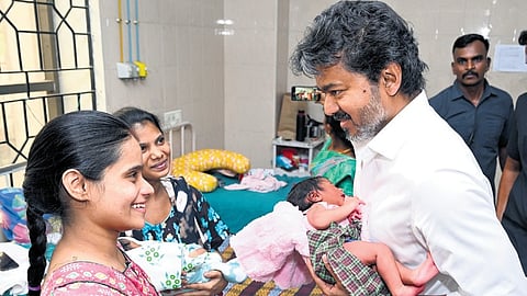 Chief Minister C Joseph Vijay holds a newborn during a surprise visit to the Government Hospital for Women and Children in Egmore on Wednesday.