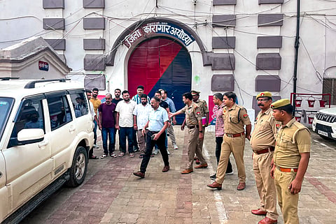 Police personnel escort three accused in the alleged Ram temple donation theft case after they were brought from jail on police custody remand, in Ayodhya, Wednesday, July 8, 2026. A local court granted one-day police remand to the accused for further investigation.