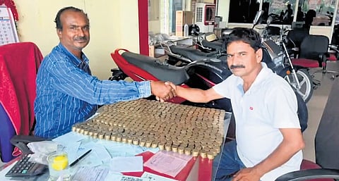 Konde Raghupathi hands over 11,000 coins of Rs 10 denomination at the motorcycle showroom in Chityal on Wednesday