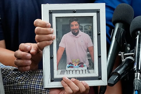 Ronaldo Salgado and Lorenzo Jr., sons of Lorenzo Salgado Araujo, hold a photograph of their father during a news conference Wednesday, July 8, 2026, in Houston