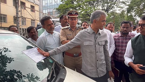 Minister Krishna Byre pastes a notice on an abandoned car at the Queens Road.