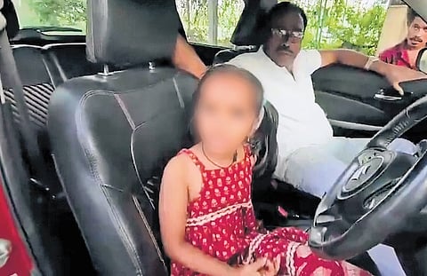 The sub-inspector in the passenger’s seat looks on as bystanders question his decision to let the six-year-old girl drive a car on the Gandhamguda-Bairagiguda main road on Saturday