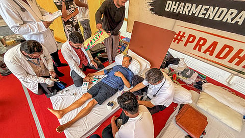 Climate activist Sonam Wangchuk being attended by a medical professional as Cockroach Janata Party (CJP) founder Abhijeet Dipke looks on during a hunger strike by at Jantar Mantar, in New Delhi, Tuesday, July 14, 2026.