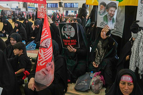 A woman holds a poster depicting U.S. President Donald Trump in the crosshairs of a rifle scope with the English words "There Will Be Blood,"as mourners gather to commemorate the late leader at the Imam Khomeini Mosalla Grand Mosque in Tehran, Iran, Tuesday, July 14, 2026.