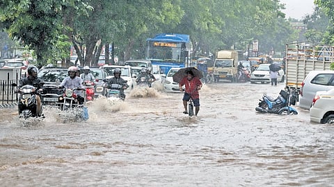 Commuters trudge through a waterlogged road at Ashok Nagar in Bhubaneswar on Thursday