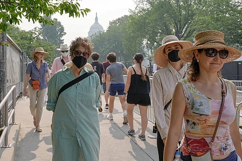 Visitors wear face masks, as smoke from wildflowers blankets the sky, Friday, July 17, 2026, in Washington.
