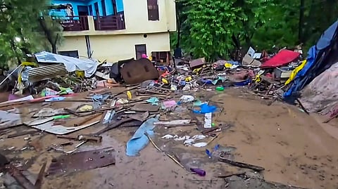 Mud, debris and damaged household items are strewn outside a residential building after flash floods caused by incessant overnight rainfall, in Rajouri, Jammu and Kashmir, Sunday,