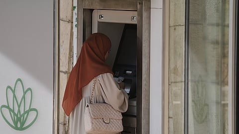 A Palestinian woman withdraws money from an ATM in the West Bank city of Bethlehem, Tuesday, July 7, 2026.