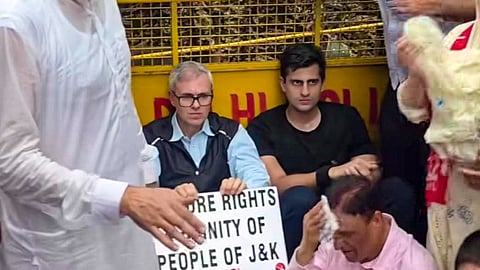 Jammu and Kashmir Chief Minister Omar Abdullah sits on a road during a protest march demanding the restoration of statehood to Jammu and Kashmir, in New Delhi.