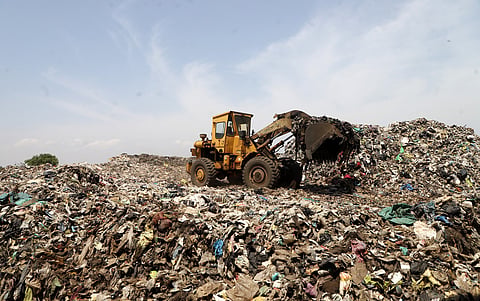 Workers transport legacy waste to the bio-mining facility at the Vellalore dumpyard in Coimbatore.