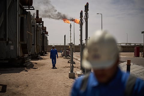 Workers walk in the Zubair oil field, whose operations have been reduced since the start of the Iran war, near Basra, Iraq, March 28, 2026.