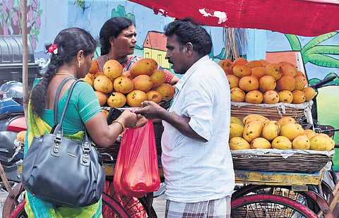 A roadside vendor sells mangoes using single-used plastic bag