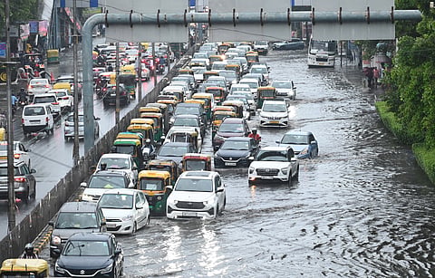 Commuters wade through waterlogged street at ITO, in New Delhi on Tuesday.