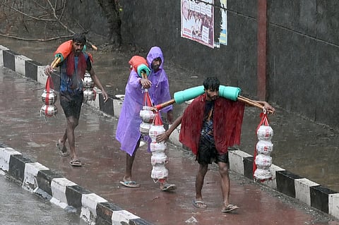 Kanwariyas, devotees of the Hindu god Shiva, walk along a road after collecting holy water from the river Ganges during the Kanwar Yatra pilgrimage in the sacred month of Sawan in New Delhi on July 28, 2026.