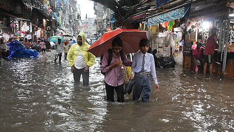 People wade through a waterlogged road amid heavy rainfall, in Sadar Bazaar area, in New Delhi.