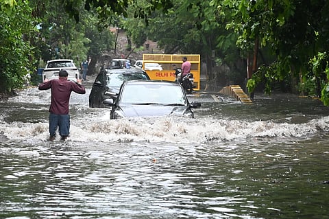 Commuters wade through waterlogged street near ITO, in New Delhi on Tuesday.