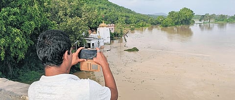 A youth takes a picture of Gokarneshwar temple, which has been submerged by Brahmani river in Dharmashala block of Jajpur district, on Thursday