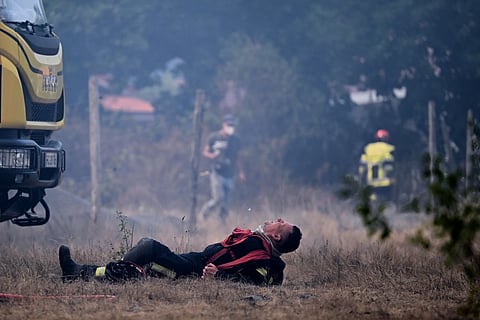 A firefighter lays on the ground after working to extinguish a fire in the forest near Blagon, during wildfires in southwestern France, Wednesday, July 29, 2026.