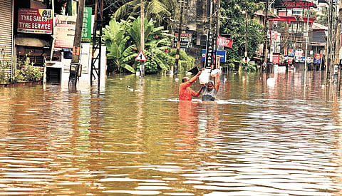 A fire and rescue services personnel escorting an elderly man carrying food to relatives who were stranded after the heavy rain submerged a road in Ranni, Pathanamthitta, on Saturday | SHAJI VETTIPURAM
