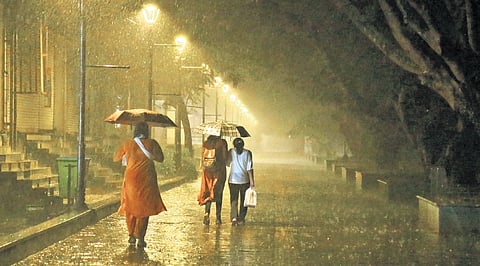 People make their way through heavy rain at Marine Drive as monsoon showers continue across Kochi.