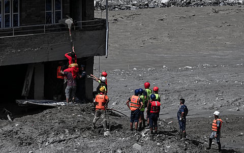 Police personnel rescue stranded residents from houses lying deluged in sludge after flash floods at Trishuli in Nepal's Nuwakot district on August 27, 2026.