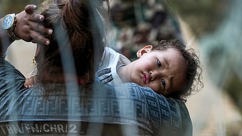 A woman carries a child in the aftermath of flash floods at Trishuli market, in Nuwakot district, Sunday, Aug. 30, 2026.