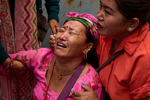 Relatives comfort woman, whose husband is missing, as she looks at photographs of people killed in flash floods displayed outside a government hospital in Kathmandu, Nepal, Sunday, Aug. 30, 2026