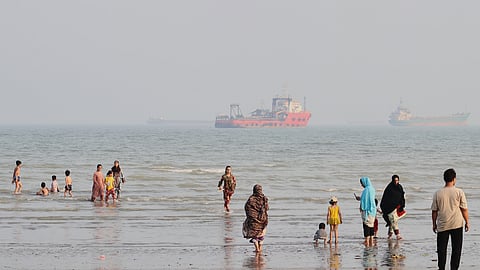 People spend time at a beach as commercial vessels are anchored in the Strait of Hormuz off Bandar Abbas, Iran, Monday, Aug. 31, 2026.
