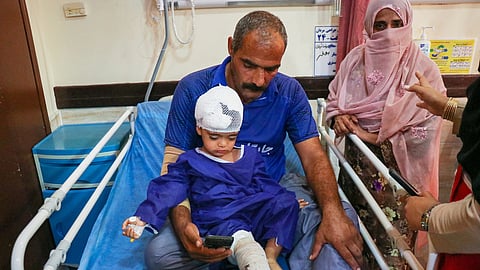 A man sits with a child injured after a US strike on a home where a wedding was being held in Kuhestak, southern Iran, at a hospital in Menab, Iran, early Wednesday, Sept. 2, 2026.