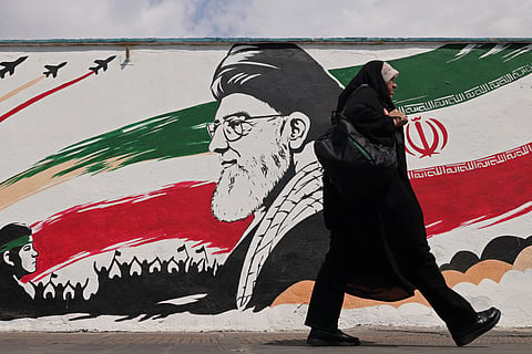 A woman walks past a wall mural of Iran's slain supreme leader Ayatollah Ali Khamenei, along a street in downtown of Tehran on August 31, 2026.